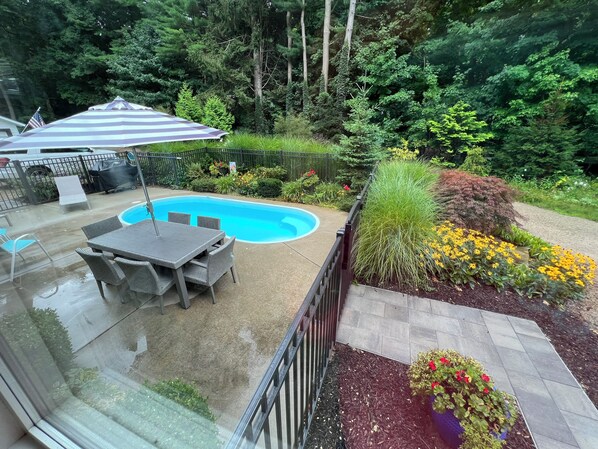 A backyard with a swimming pool, patio furniture, and a variety of plants and flowers. - Ultimate Family Retreat: Pool, Huge Yard, Gardens, Chickens, 5 Beaches Closeby (Fennville)