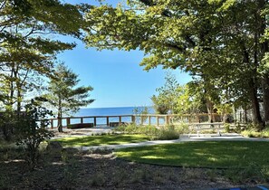 Vista sulla costa con un pontile in legno, zone verdi e alberi.