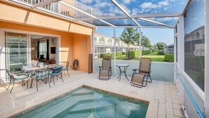 A covered outdoor pool area with a table and chairs, a hot tub, and a view of neighboring houses. - Cutest Vacation Home Ever! (Clermont)