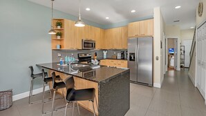 A modern kitchen with a central island, stainless steel appliances, and bar stools. - Cutest Vacation Home Ever! (Clermont)