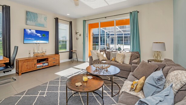 A modern living room with a sofa, coffee table, and TV. - Cutest Vacation Home Ever! (Clermont)