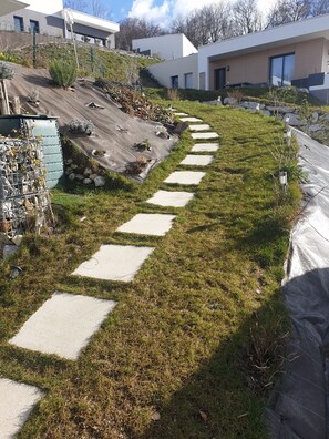 A modern residential area with a paved pathway, a small garden, and a building with a flat roof.