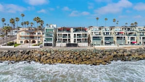 Ein Strandhotel mit mehreren Balkonen, einer felsigen Küstenlinie und Palmen.