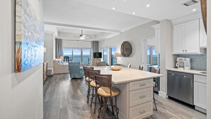 A spacious kitchen with a large island, bar stools, and a view to the outside.