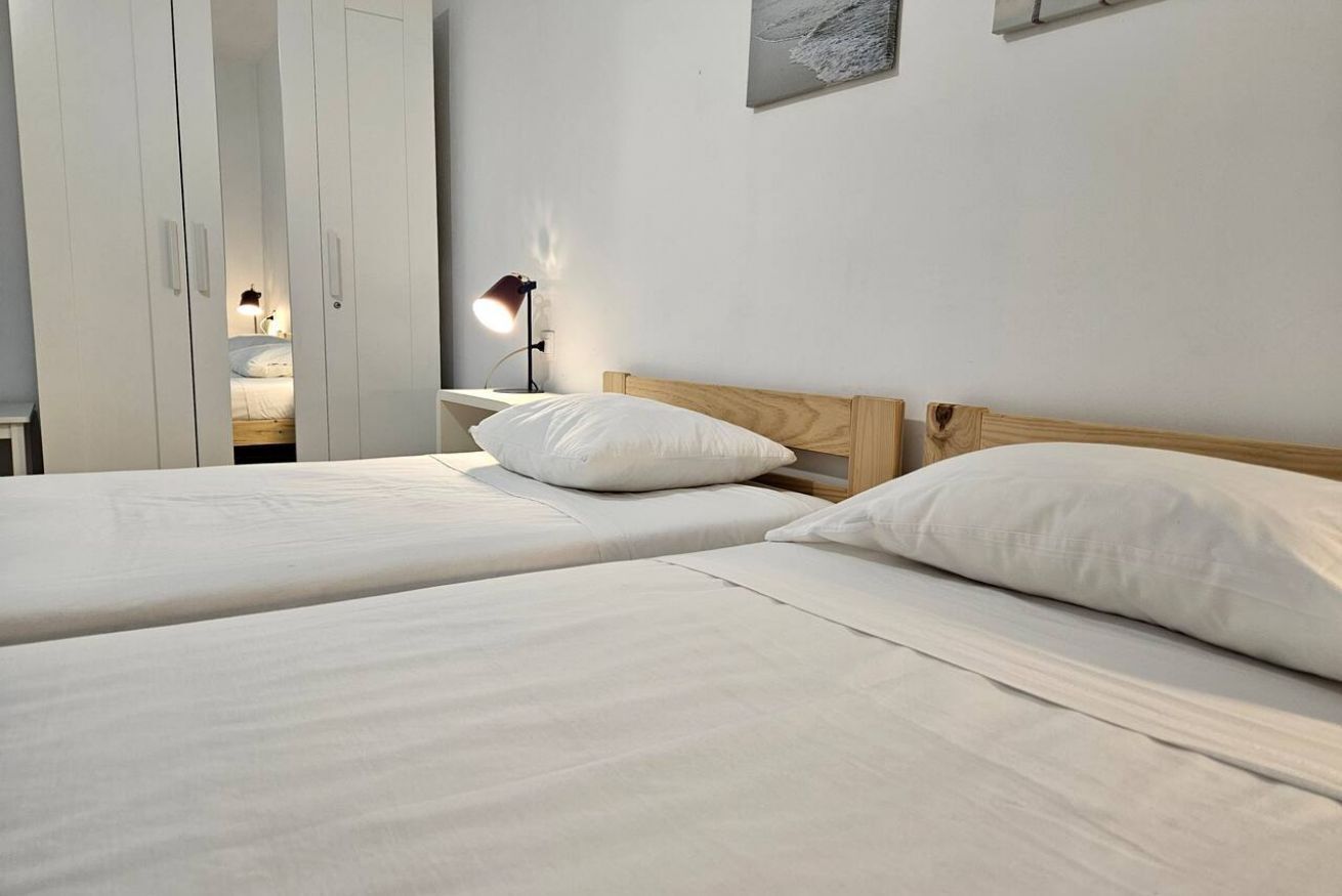 Une chambre avec deux lits, une table de chevet avec une lampe et une armoire.