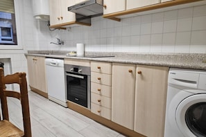 A kitchen with wooden cabinets, a dishwasher, an oven, and a washing machine.