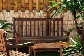 Un banc et une table en bois, placés contre un mur en bambou.