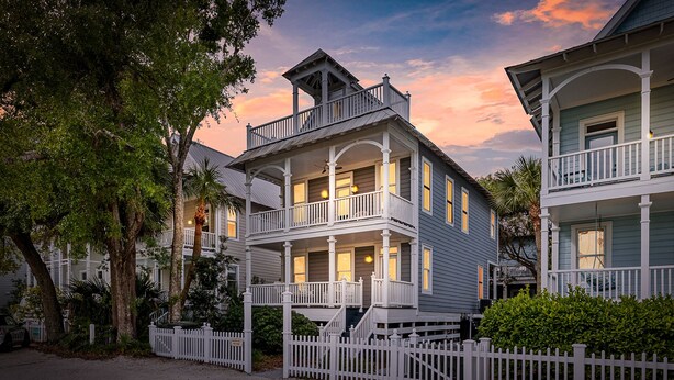 Une maison à deux étages avec un balcon, une véranda et une clôture blanche en bois.
