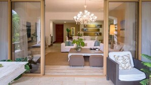 A modern living room with a glass partition, a chandelier, a sofa, a coffee table, and a dining area. - Chic luxury condo at Los Altos Casa de Campo (La Romana)