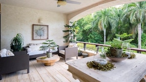 A spacious balcony with a ceiling fan, comfortable seating, and various potted plants. - Chic luxury condo at Los Altos Casa de Campo (La Romana)