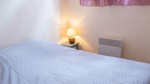 A single bed with a patterned bedspread, a bedside table with a lamp, and a wall-mounted heater. - Homerez - Chalet in Darazac (Darazac)