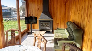 Ein gemütliches Zimmer mit Holzvertäfelung, einem Kamin, einem Fernseher und einem Sofa.