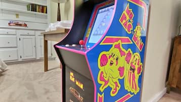 Ein Pac-Man-Automaten-Spiel in einem Raum mit Teppichboden, weißen Schränken und einer Lampe.