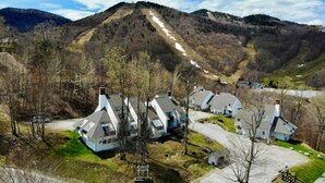 A residential area with houses, a winding road, and a mountain in the background. - SunBear- AC, Pool, Game Room, Fireplace, Hiking! (Killington)