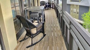 A covered porch with a table and chairs, a wooden floor, and a view of neighboring houses.