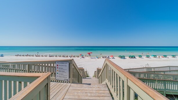 A wooden boardwalk leading to a beach with clear skies.