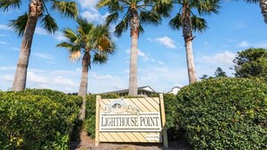A sign for Lighthouse Point with palm trees and a clear sky. - Lighthouse Point 13B | Oceanfront Condo, Pool! (Tybee Island)