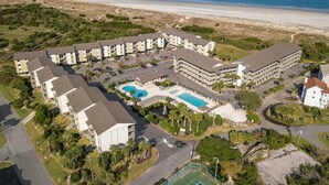 An aerial view of a resort with multiple buildings, a swimming pool, and a beach in the background. - Lighthouse Point 13B | Oceanfront Condo, Pool! (Tybee Island)