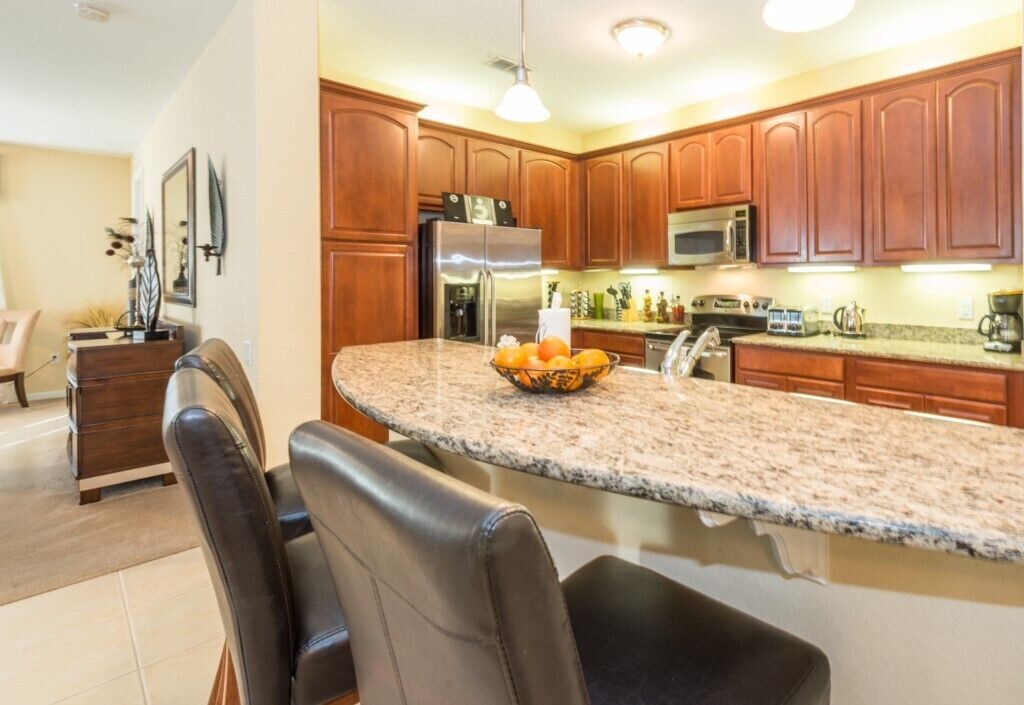 A kitchen with wooden cabinets, a granite countertop, and a stainless steel refrigerator.