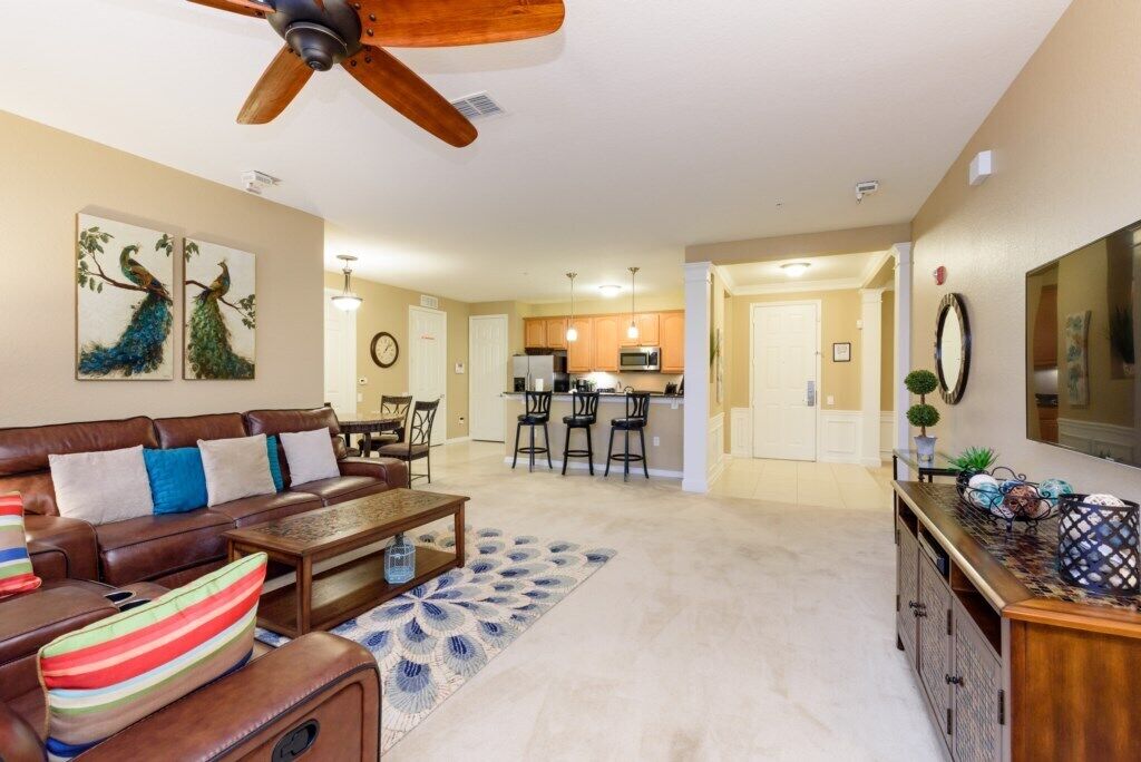 A living room with a brown leather sofa, a coffee table, and a ceiling fan.