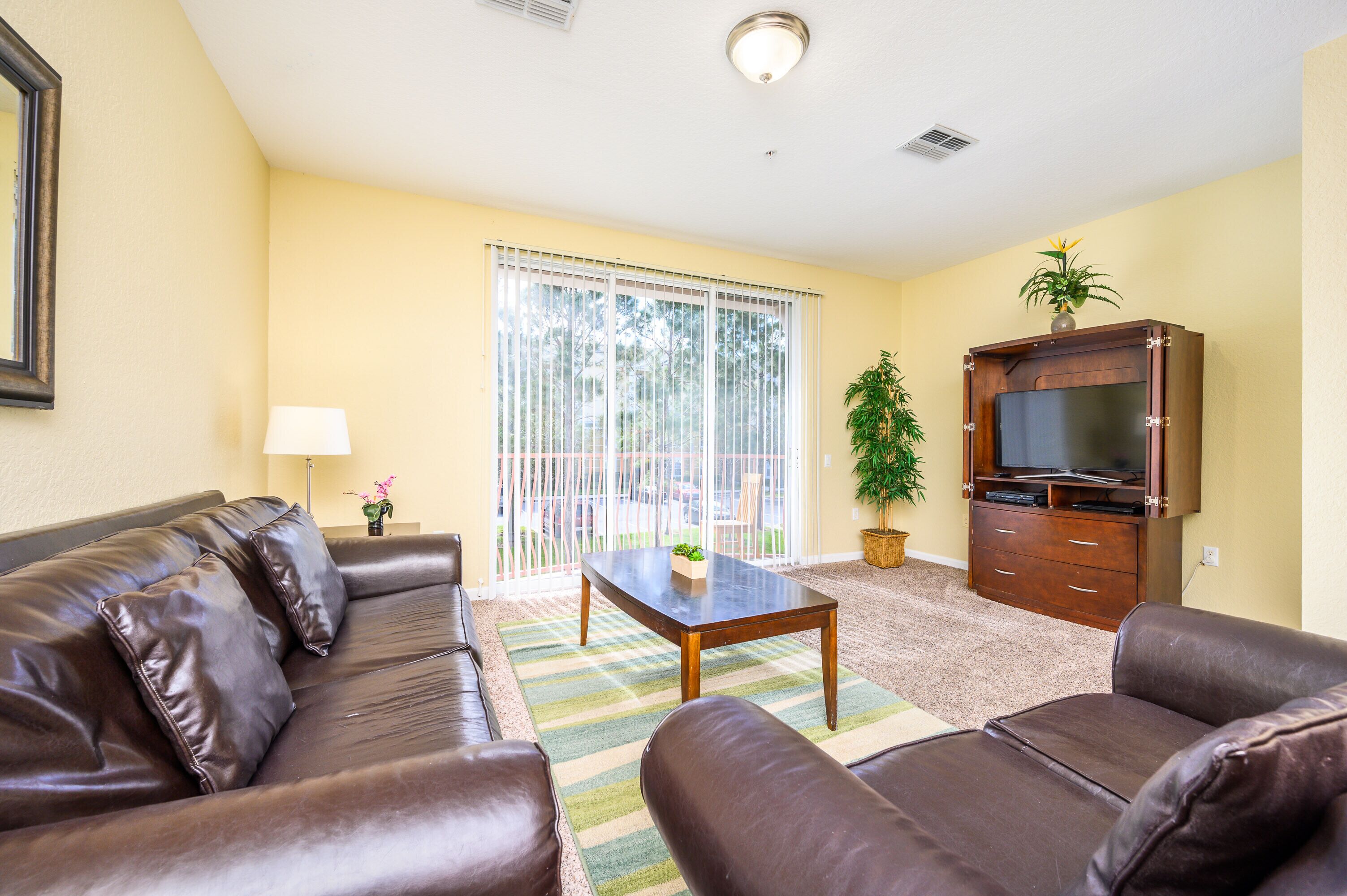 A living room with a brown leather sofa, a wooden coffee table, and a television cabinet.