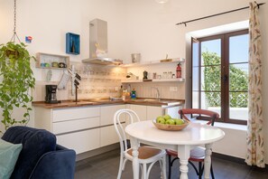 Eine moderne Küche mit weißen Schränken, einer Holz Arbeitsplatte und einem Essbereich mit Tisch und Stühlen.