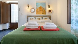 A hotel room with a bed, two towels, a painting, and a view of the outside. - Apartment Blue, Casa El Patio (Adults Only) (Teguise (Lanzarote))