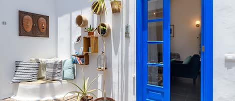 Una habitación con una puerta azul, pared blanca y varias plantas en macetas.