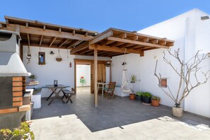 An outdoor patio with a wooden pergola, a grill, and potted plants. - Apartment Blue, Casa El Patio (Adults Only) (Teguise (Lanzarote))
