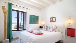 Un dormitorio con cama, una ventana con cortinas, un cuadro, luces empotradas en la pared y un armario rojo.