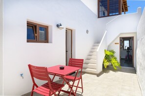 A small patio with a red table and chairs, a staircase, and a potted plant.