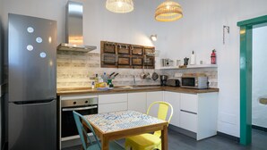 A modern kitchen with a stainless steel refrigerator, a Bosch range hood, a wooden backsplash, a microwave, and a dining area with a patterned table and two chairs. - Apartment Green, Casa El Patio (Only Adults) (Teguise (Lanzarote))