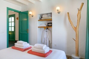 Een hotelkamer met een bed, een houten plank met handdoeken, een badjas en een decoratief houten object.