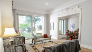 Een ruime woonkamer met een bank, salontafel en een eethoek met stoelen en een tafel.