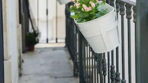 Ein schmaler Balkon mit Metallgeländern und hängenden Blumentöpfen.