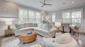 A spacious living room with a sectional sofa, a round wicker coffee table, and a dining area with wicker chairs. - Current Situation| 4 Bdrm w/ 3 Kings | Heated Pool | Golf Cart (Santa Rosa Beach)