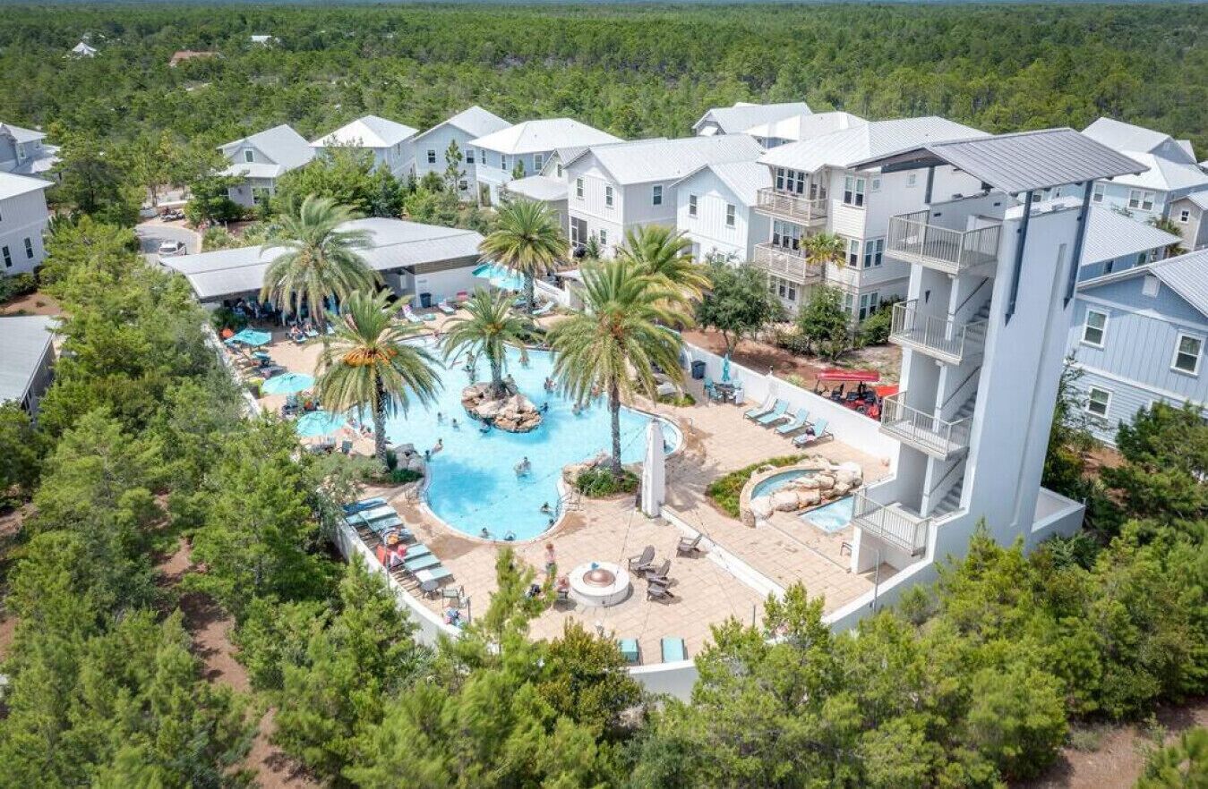 A resort with multiple buildings, a central swimming pool, and surrounding greenery.