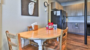 A dining area with a wooden table and chairs, a clock on the wall, and a kitchen with wooden cabinets and a refrigerator. - Hidden Gem: Dock & Views on Pine Hollow Reservoir! (Tygh Valley)