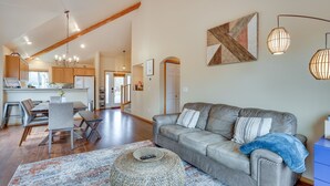 Ein großzügiges Wohnzimmer mit grauem Sofa, einem Couchtisch und einem Essbereich mit Holztisch und Stühlen.