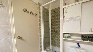 A bathroom with a shower, toilet, and shelves with toiletries. - AGREABLE STUDIO EN REZ DE JARDIN AVEC GRANDE TERRASSE (LE CAP D AGDE)