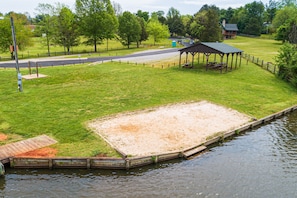 Enjoy a serene lakeside retreat with a grassy area, wooden dock, and shaded picnic shelter.