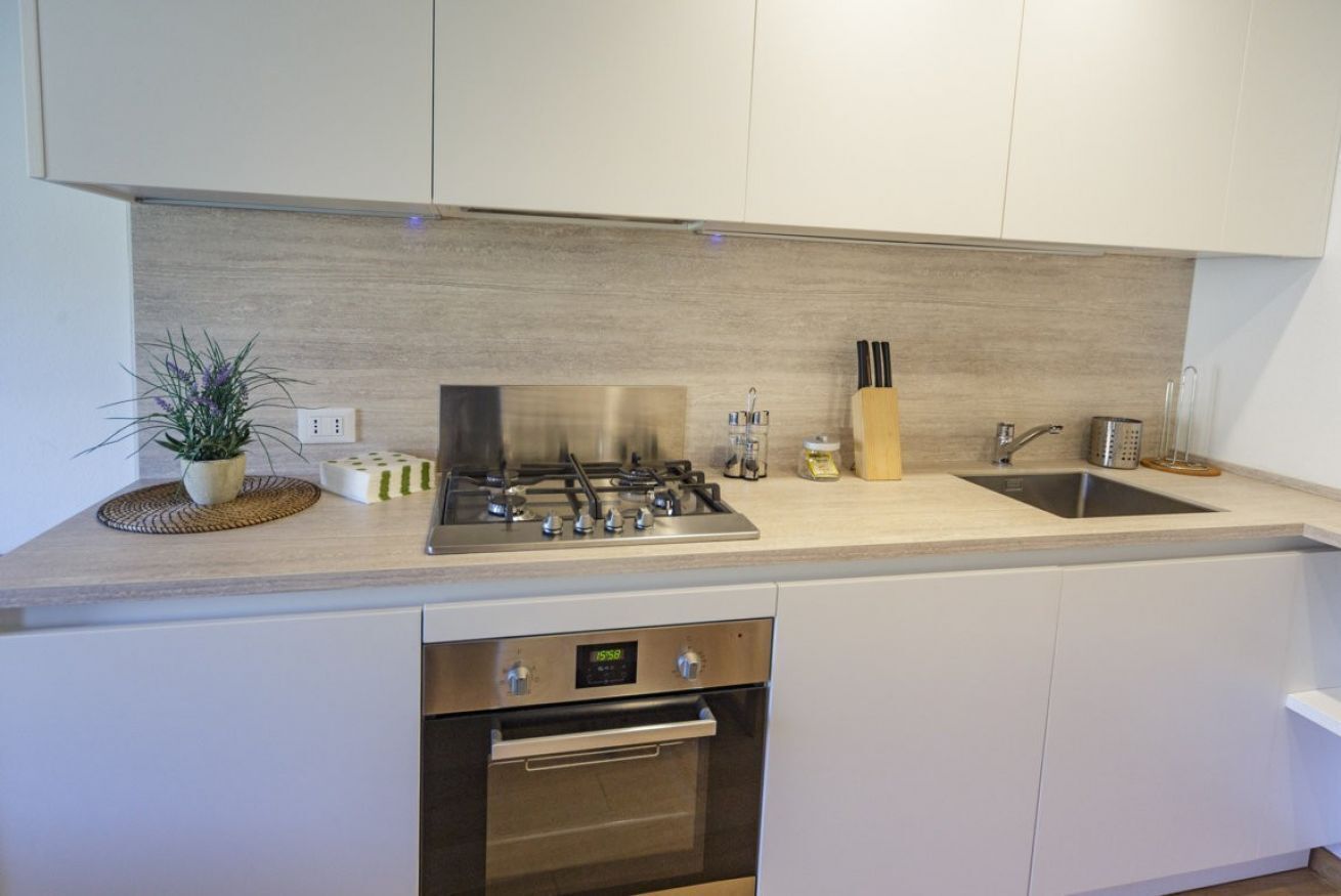 Una cocina moderna con estufa a gas, horno y pileta de acero inoxidable.