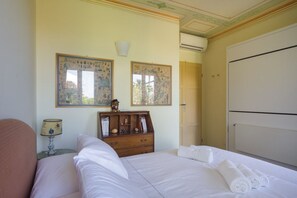 Habitación de hotel con cama, mesita de noche con lámpara, cómoda y dos cuadros en la pared.