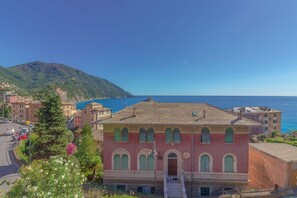Un edificio costero con fachada roja, una escalera y vista al mar.