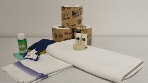 Aparato de baño con una toalla blanca, una botella verde de Lemure, una esponja azul y dos botellas de Papernet.