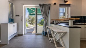 Une cuisine moderne dotée d’une porte-fenêtre coulissante donnant sur un patio, d’un petit îlot avec des tabourets et offrant une vue sur l’extérieur.