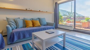 A modern living room with a sofa, a coffee table, a large window with a view of a mountain, and a radiator. - HAPPY HOLIDAY - Open space with sea view (Camogli)