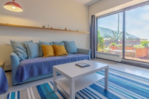 Un salon moderne avec un canapé, une table basse, une grande fenêtre donnant sur une montagne et un radiateur.