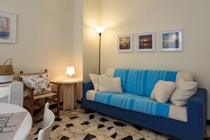 A cozy room with a blue sofa, a small table, a lamp, and a chair.