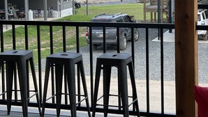 Una terraza con asientos al aire libre, vista a un río y una colina boscosa de fondo.